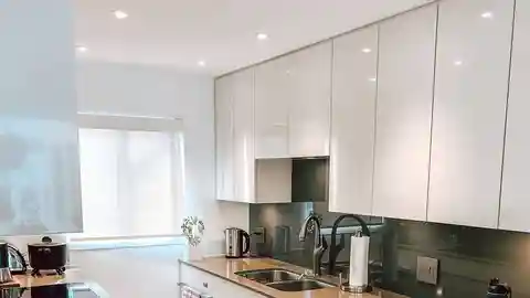 Basement suite kitchen with recessed pot lights, range hood, and glass backsplash