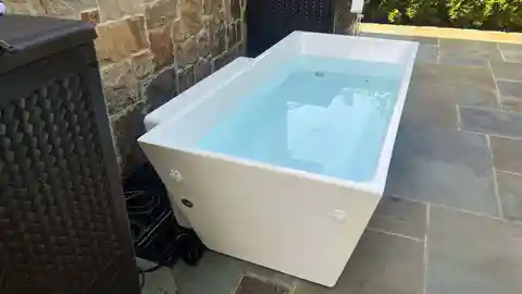 White cold plunge pool on stone patio with electrical hookup
