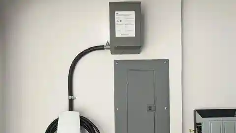 DCC load management system with Tesla charger and sub-panel on white wall