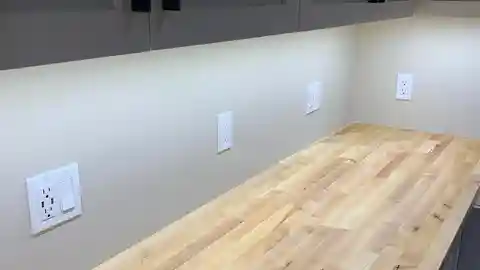 Under-cabinet LED lighting on butcher block workbench with multiple outlets