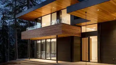 Modern cedar home at dusk with soffit pot lights and large windows