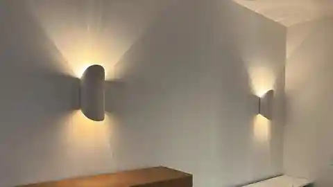 Two modern white wall sconces casting light up and down in hallway